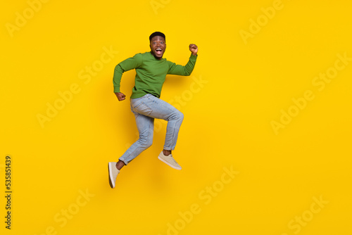 Full length body size view of attractive cheerful funny guy jumping running isolated over shine yellow color background