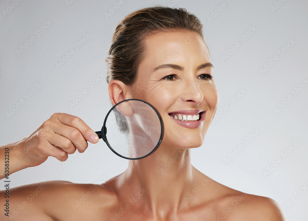 Mature woman, skincare and smile magnifying glass to zoom on face for health, wellness and facial beauty. Model, happy and skin show happiness with natural glow against cosmetics studio background Mature woman, skincare and smile magnifying glass to zoom on face for health, wellness and facial beauty. Model, happy and skin show happiness with natural glow against cosmetics studio background