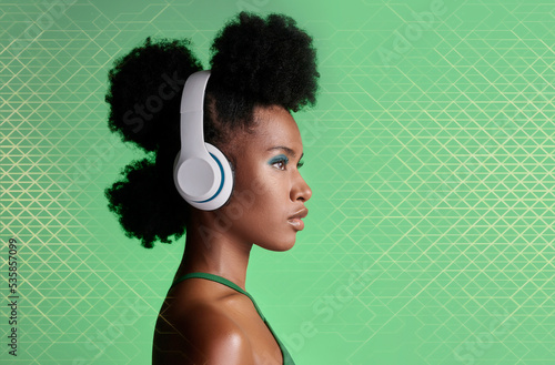 Black woman, music headphones and fashion hairstyle on studio background with green geometric patterns and makeup cosmetics. Style, trend or pride for beauty model listening to Jamaican radio podcast photo
