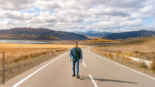 a man walks along an autumn road. the guy in jeans in autumn
