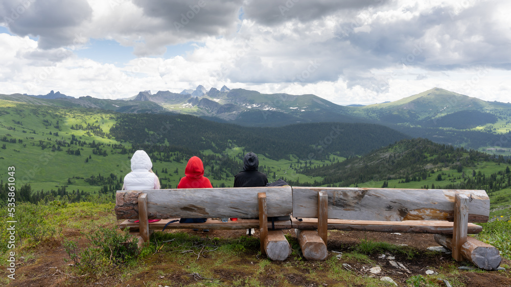 People on a bench against the background of mountains in summer