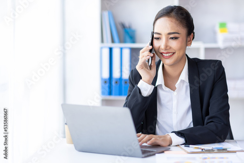 Beautiful Young business Asian Woman Talking on Smartphone in workplace