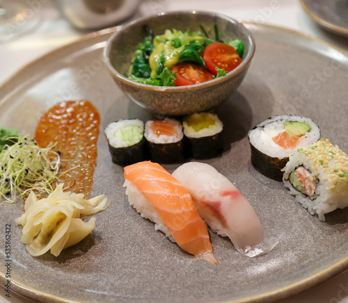 Ein Teller mit Salat und Sushi Rollen, frischer roher Fisch. photo