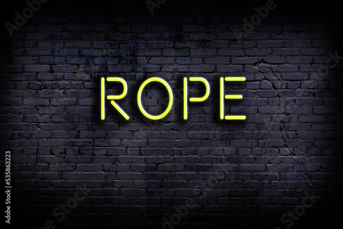 Neon sign. Word rope against brick wall. Night view photo