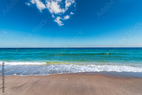 waves crashing on beach with cloud in blue sky