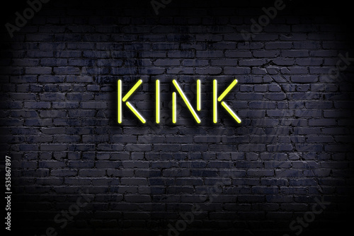 Night view of neon sign on brick wall with inscription kink