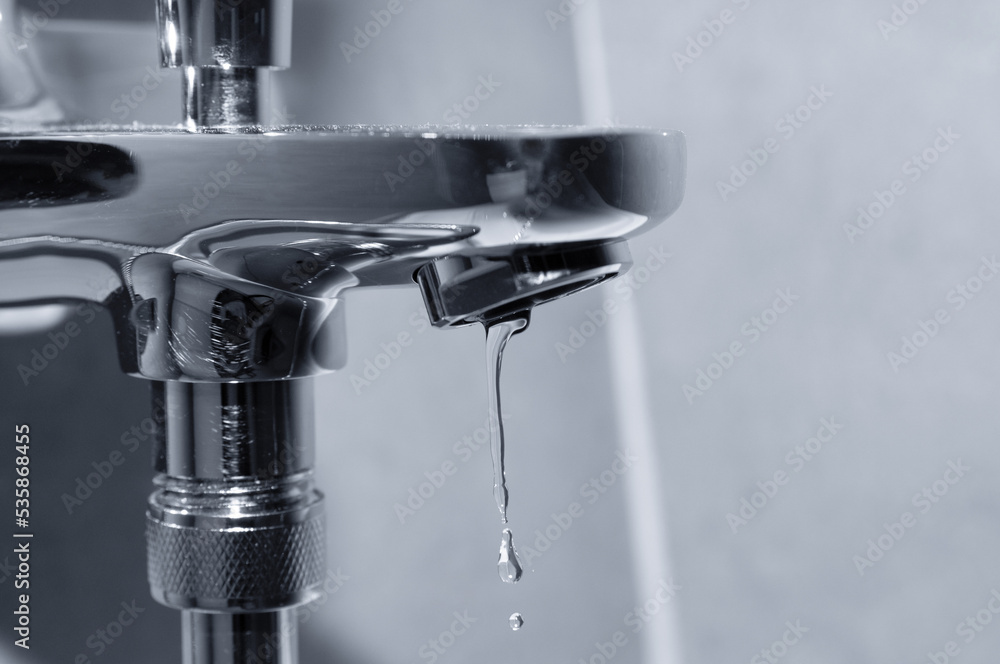 Water drop close up dripping from chrome faucet Water drop close up dripping from chrome faucet