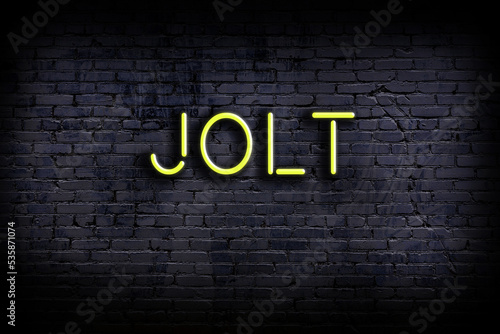 Night view of neon sign on brick wall with inscription jolt