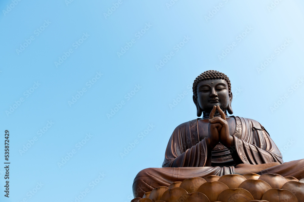 Fototapeta premium Wooden Buddha statue under blue sky