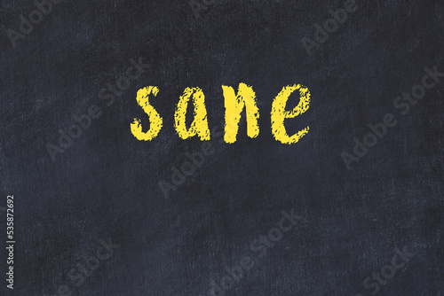 College chalk desk with the word sane written on in