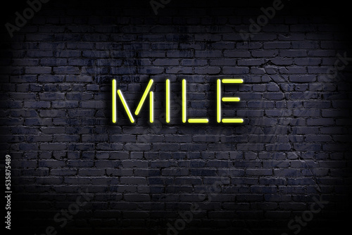 Neon sign. Word mile against brick wall. Night view photo