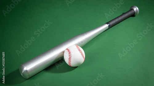 Baseball bat and baseball on the green background.
