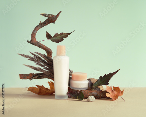 Set of empty cosmetic packaging, jar and bottle, mockup, against the background of autumn props. Autumn modern still life.