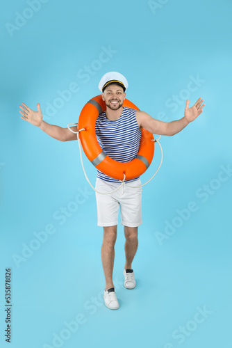 Happy sailor with orange ring buoy on light blue background