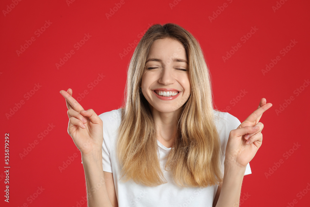 Woman with crossed fingers on red background. Superstition concept Woman with crossed fingers on red background. Superstition concept