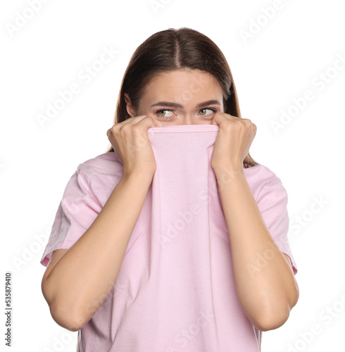 Embarrassed young woman covering face with shirt on white background