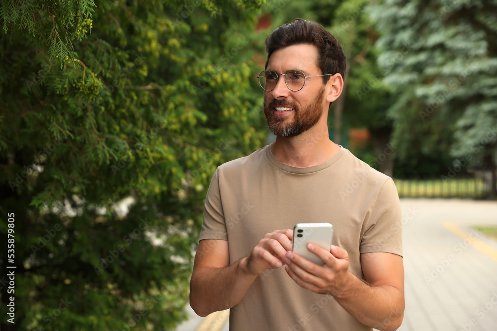 Smiling handsome bearded man with smartphone outdoors. Space for text Smiling handsome bearded man with smartphone outdoors. Space for text
