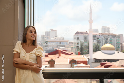 Beautiful young woman standing on balcony, space for text © New Africa