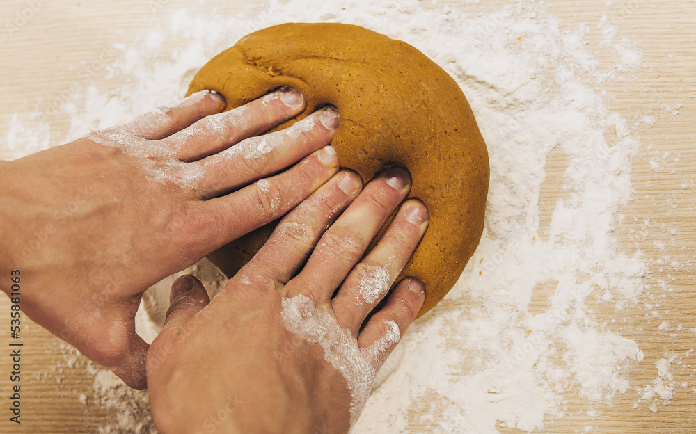 Men's hands knead the dough. The chef prepares ginger. Christmas cookies on the table with cooking flour. Men's hands knead the dough. The chef prepares ginger. Christmas cookies on the table with cooking flour.