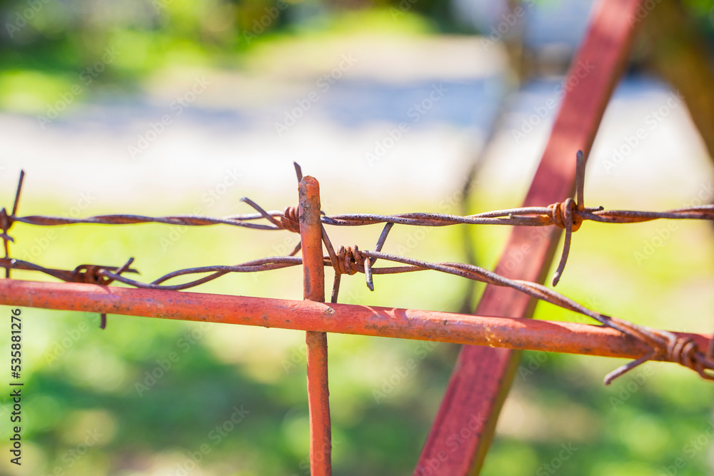close-up of barbed wire fencing private territory from unauthorized persons painted red. Escape. close-up of barbed wire fencing private territory from unauthorized persons painted red. Escape.