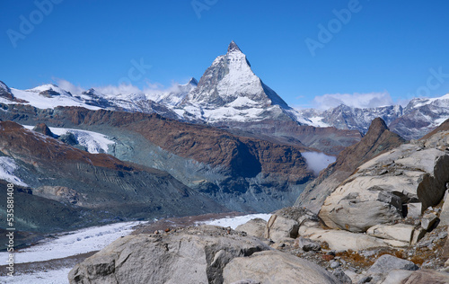 Panoramic view on the iconic mount Matterhorn at background and the Border glacier Grenz Gletscher at foreground in a sunny autumn day, seen from hiking trail to the Monte Rosa mountain hut. Zermatt.