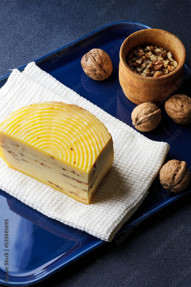 A piece of cheese served with walnuts on the blue tray