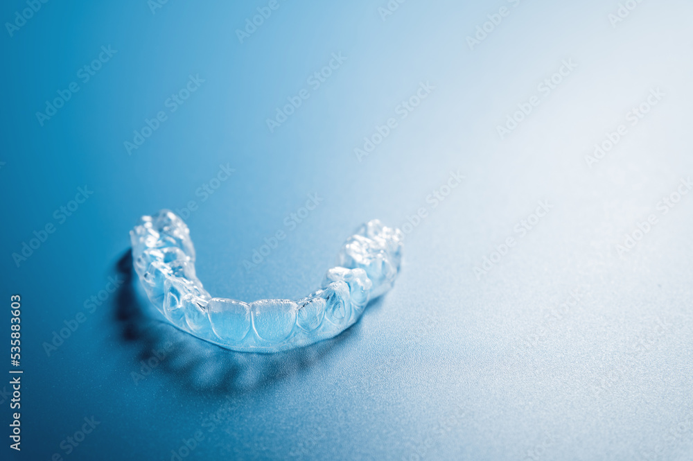 Close up invisible aligners on the blue background with copy space. Plastic braces dentistry retainers to straighten teeth Close up invisible aligners on the blue background with copy space. Plastic braces dentistry retainers to straighten teeth