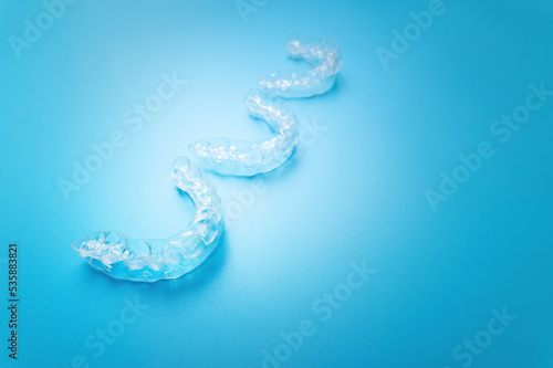 close-up, new transparent braces lie in a row on a blue background. suitable for dental clinic banner