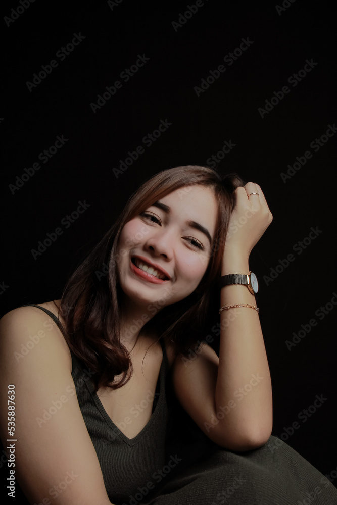 young Asian women wear dresses or dark clothes. Take pictures and express themselves inside the indoor studio. On a dark black background. young Asian women wear dresses or dark clothes. Take pictures and express themselves inside the indoor studio. On a dark black background.