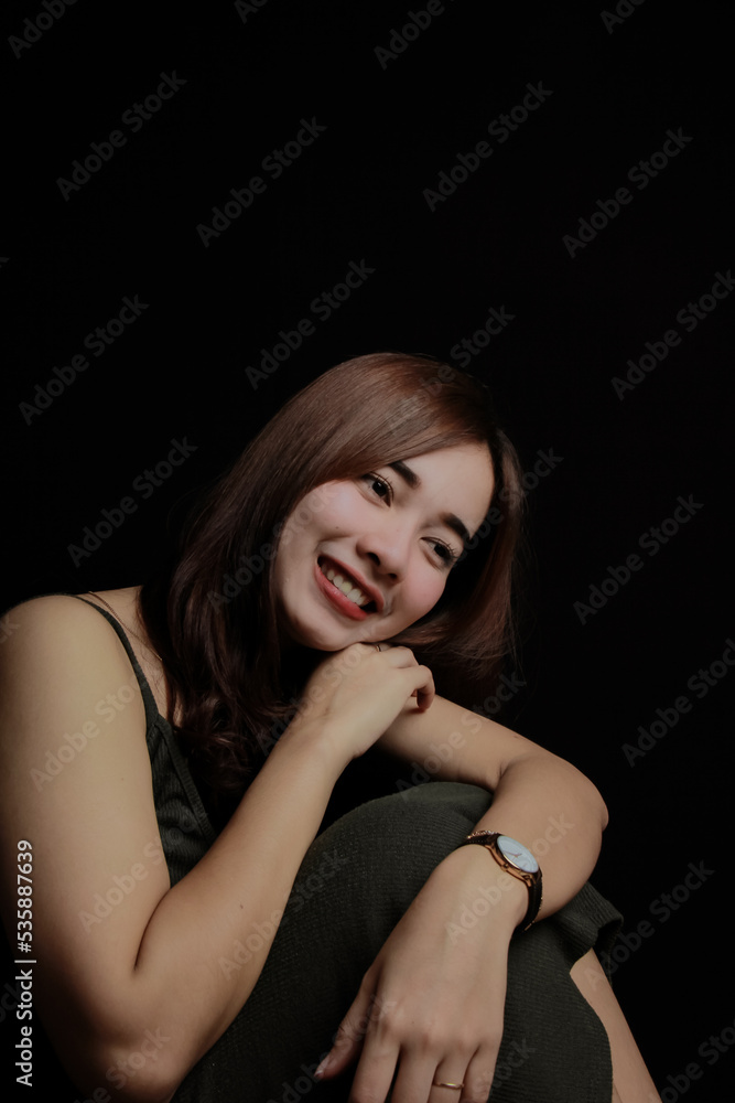 young Asian women wear dresses or dark clothes. Take pictures and express themselves inside the indoor studio. On a dark black background. young Asian women wear dresses or dark clothes. Take pictures and express themselves inside the indoor studio. On a dark black background.