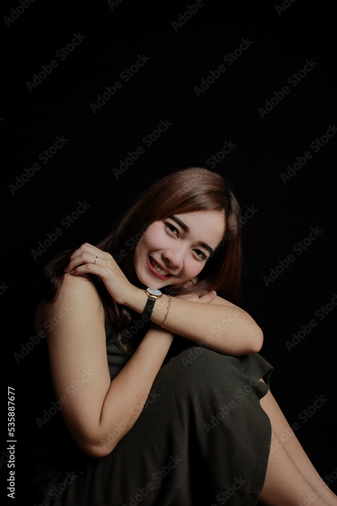 young Asian women wear dresses or dark clothes. Take pictures and express themselves inside the indoor studio. On a dark black background. young Asian women wear dresses or dark clothes. Take pictures and express themselves inside the indoor studio. On a dark black background.