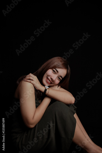 young Asian women wear dresses or dark clothes. Take pictures and express themselves inside the indoor studio. On a dark black background.