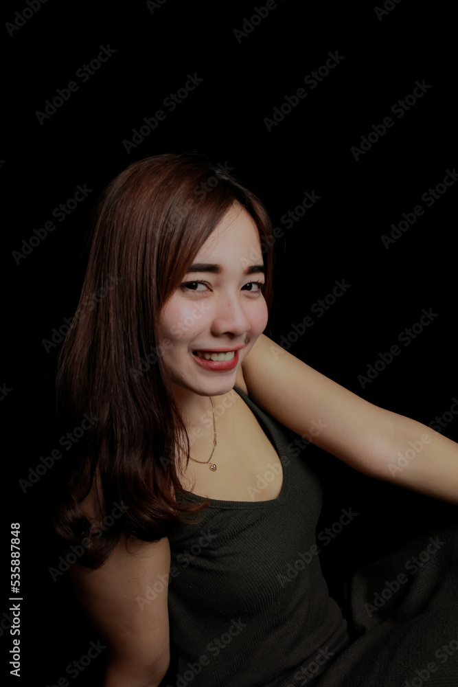 young Asian women wear dresses or dark clothes. Take pictures and express themselves inside the indoor studio. On a dark black background. young Asian women wear dresses or dark clothes. Take pictures and express themselves inside the indoor studio. On a dark black background.