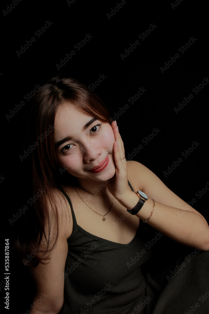 young Asian women wear dresses or dark clothes. Take pictures and express themselves inside the indoor studio. On a dark black background. young Asian women wear dresses or dark clothes. Take pictures and express themselves inside the indoor studio. On a dark black background.