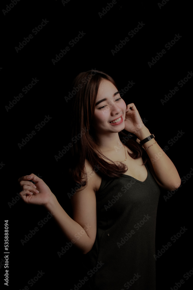 young Asian women wear dresses or dark clothes. Take pictures and express themselves inside the indoor studio. On a dark black background. young Asian women wear dresses or dark clothes. Take pictures and express themselves inside the indoor studio. On a dark black background.