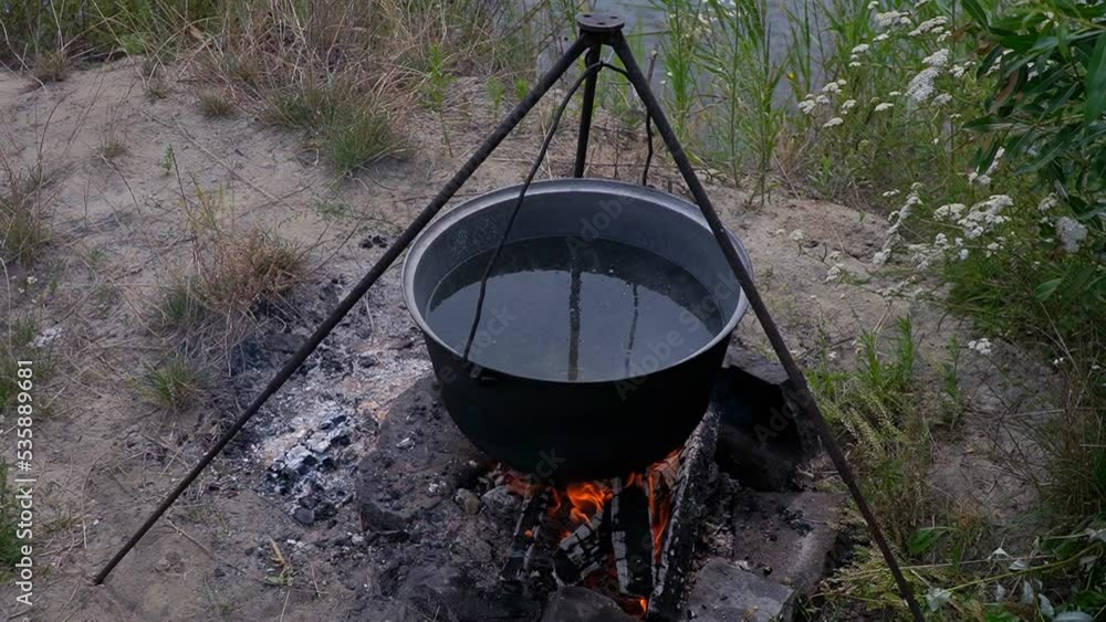 Hiking pot, Bowler in the bonfire. in cauldron at the stake. Traveling, tourism, picnic cooking, cooking at the stake in a cauldron, fire and smoke. Hiking pot, Bowler in the bonfire. in cauldron at the stake. Traveling, tourism, picnic cooking, cooking at the stake in a cauldron, fire and smoke.