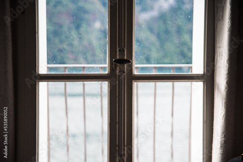 A window with Lake Lugano in the background in Switzerland during the summer. 