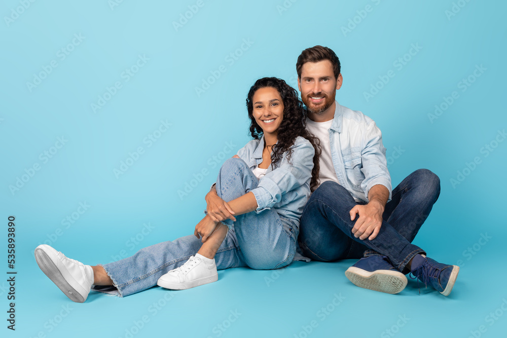 Smiling handsome millennial european male and arab woman hugs, sits on floor, enjoy spare time Smiling handsome millennial european male and arab woman hugs, sits on floor, enjoy spare time