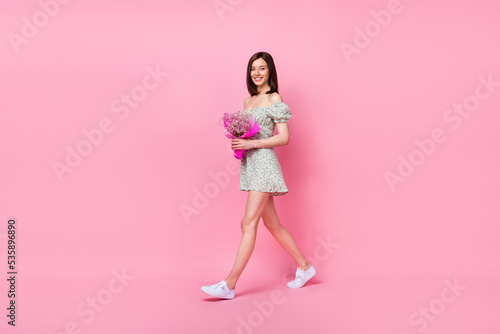 Full body photo of cheerful positive pretty girl walking give mom present woman day empty space isolated on pink color background