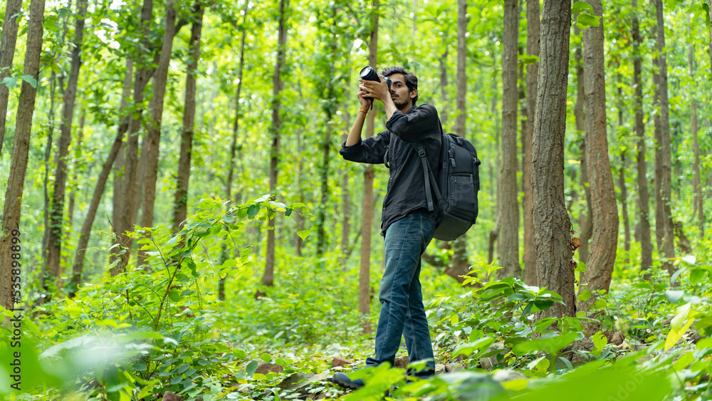 Young photographer standing in the nature, taking picture with professional camera Young photographer standing in the nature, taking picture with professional camera