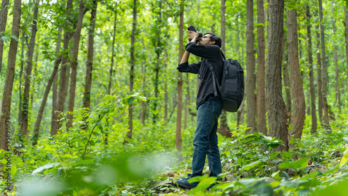 Photography Young photographer standing in the nature, taking picture with professional came