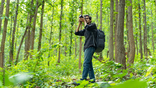 Photography Young photographer standing in the nature, taking picture with professional came