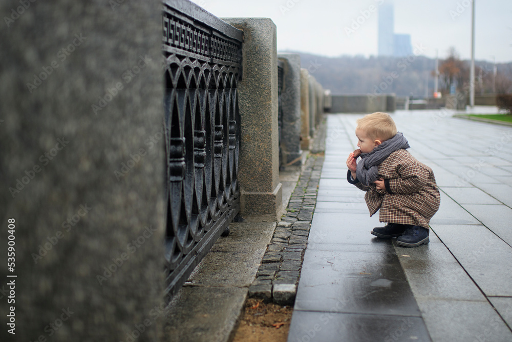 little boy squatting by the parapet little boy squatting by the parapet