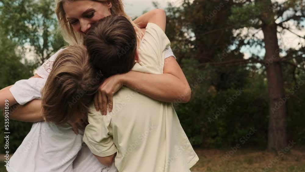 Two sons of different ages run to their mother and hug her. Two sons of different ages run to their mother and hug her.