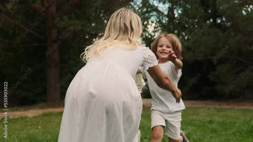 Two sons of different ages run to their mother and hug her. Two sons of different ages run to their mother and hug her.