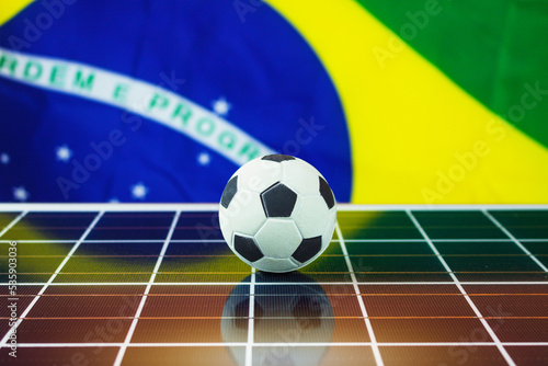 Soccer Ball and Brazil Flag over Photovoltaic Solar Panel. World Cup and Technology Concept Image for Design.