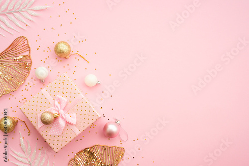 Present box at pink background with holiday decorations. White and golden christmas decorations flat lay with space for your text.