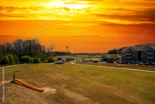 a gorgeous autumn landscape at The Walk at Sandy Run surrounded by yellow winter grass and lush green trees and brown apartment buildings with powerful clouds at sunset in Warner Robins Georgia USA photo