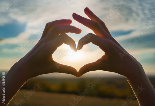 The silhouette of the hands of a baby girl symbol of the heart with hands at sunset