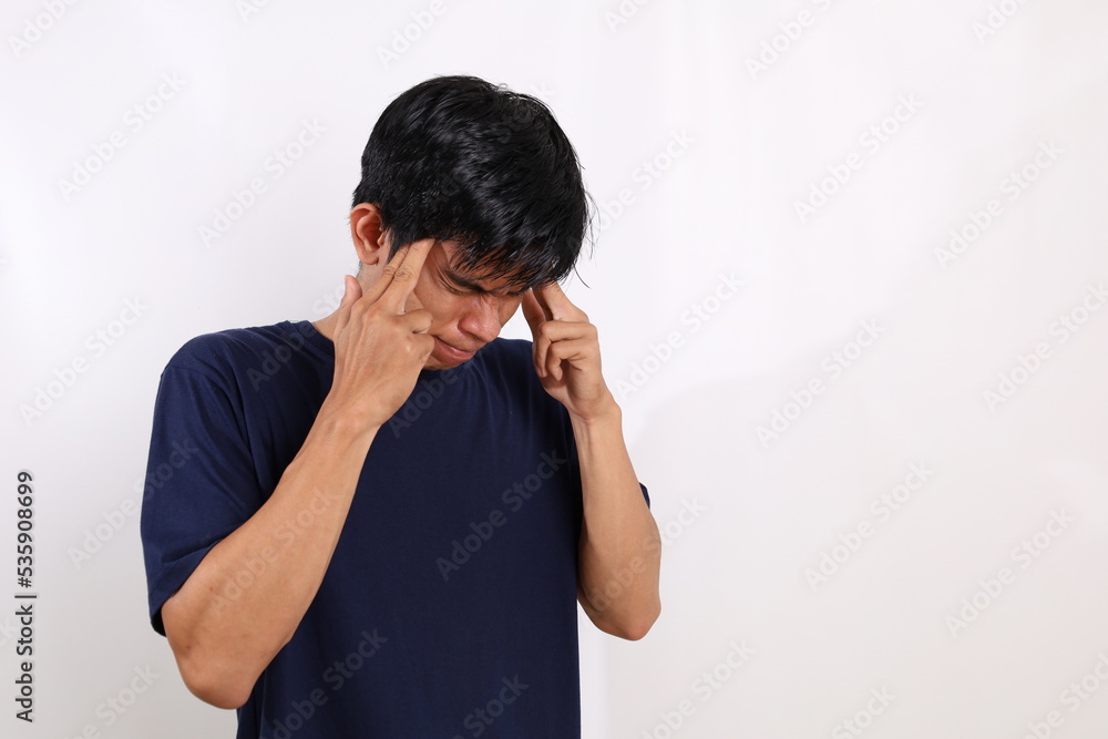 Stressed asian young man suffering from headache. Isolated on white background with copyspace Stressed asian young man suffering from headache. Isolated on white background with copyspace